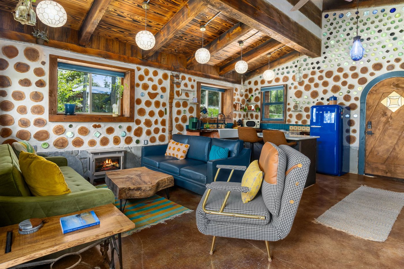Goldfinch open living room with velvet sofas and a cordwood wall