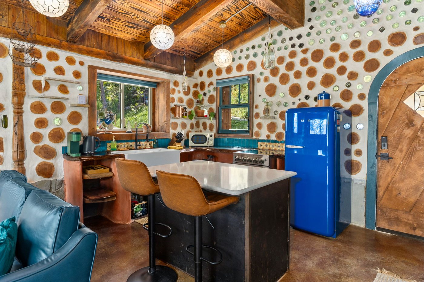 Goldfinch kitchen island and blue retro fridge beside an arched wood door