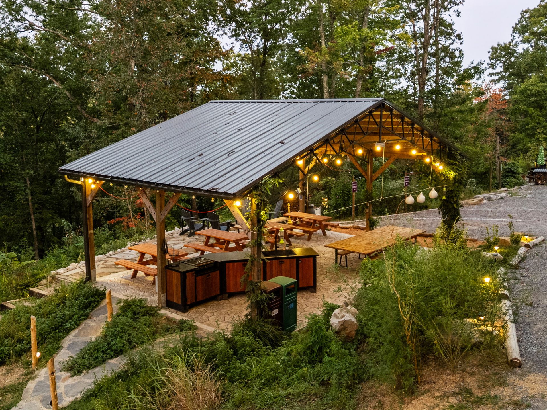 The Songbird Pavilion and its long tables seen from the slope above at dusk
