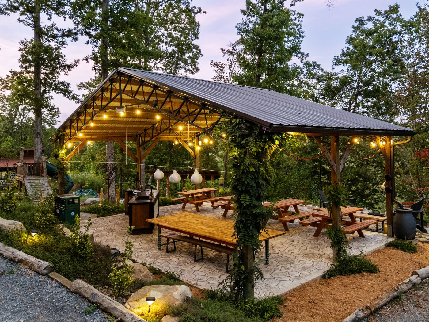 The Songbird Pavilion lit with string lights over the long tables at dusk