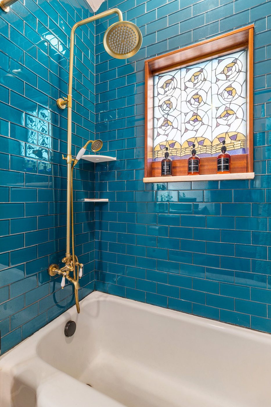 Whippoorwill indoor shower with blue tile and a stained-glass window
