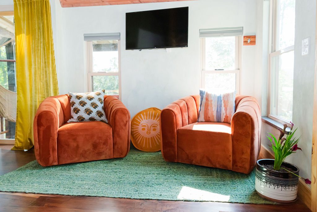 Blackbird living area with orange velvet chairs and TV