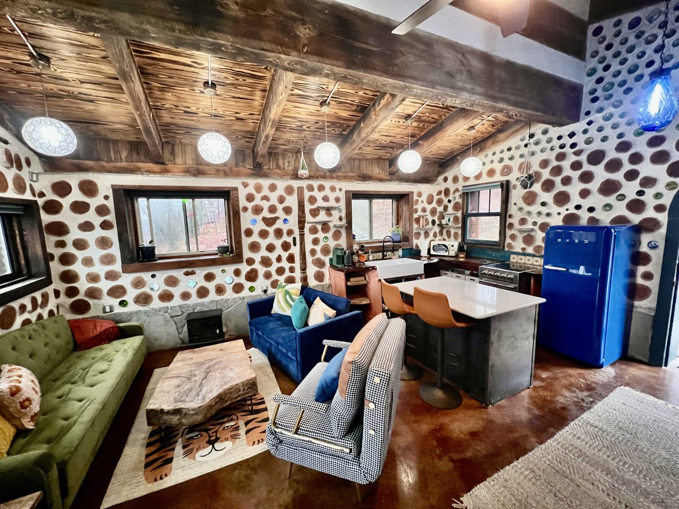 Goldfinch open living and kitchen with cordwood and bottle-glass walls