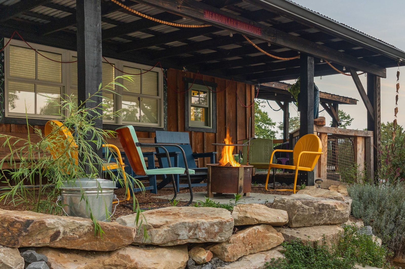 Meadowlark porch firepit ringed with colorful metal chairs