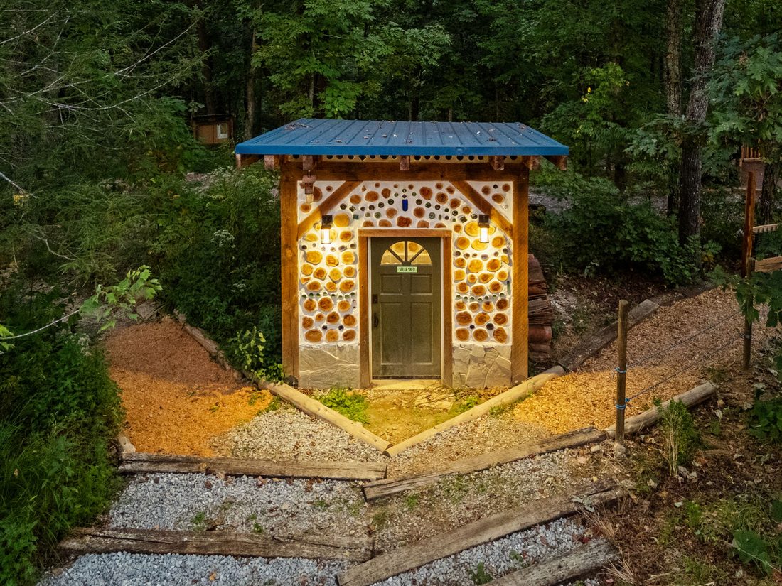 A cordwood hut lit up at dusk
