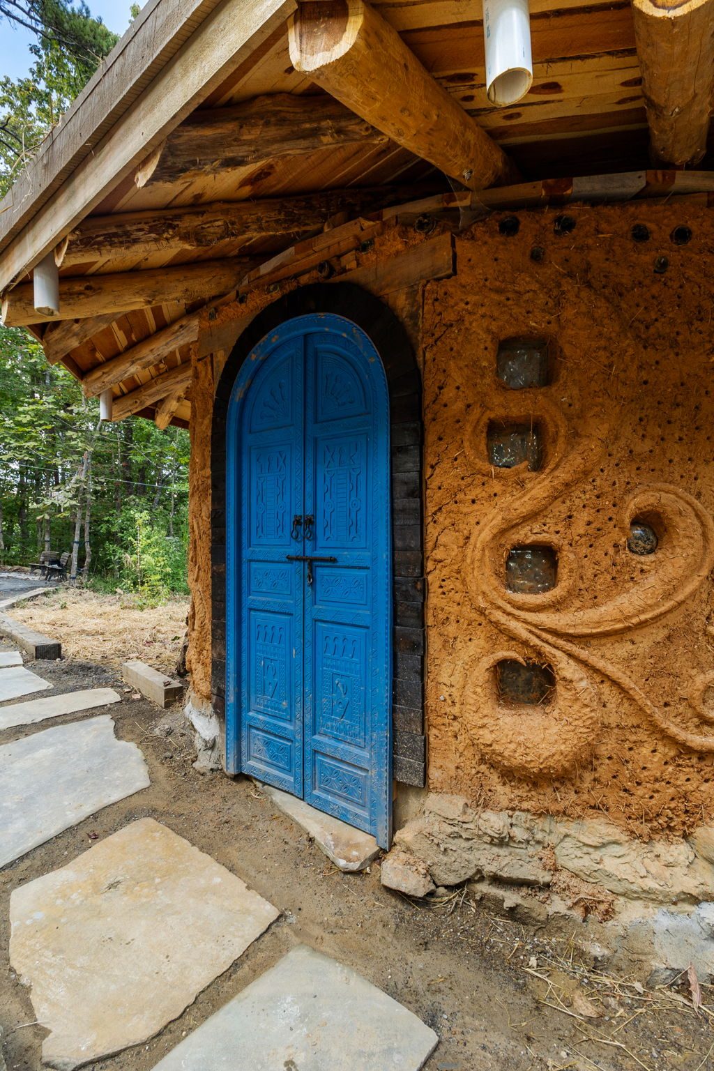 A sculpted cob wall with a blue double door